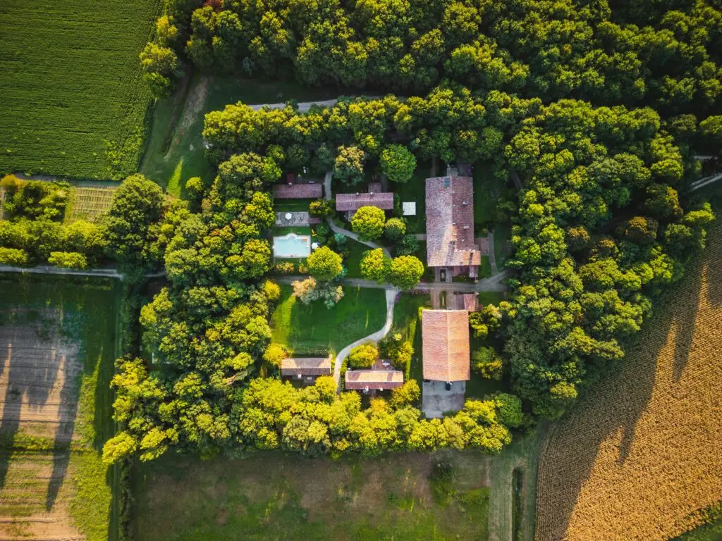 Aerial view capturing a serene estate surrounded by lush trees and vibrant greenery.