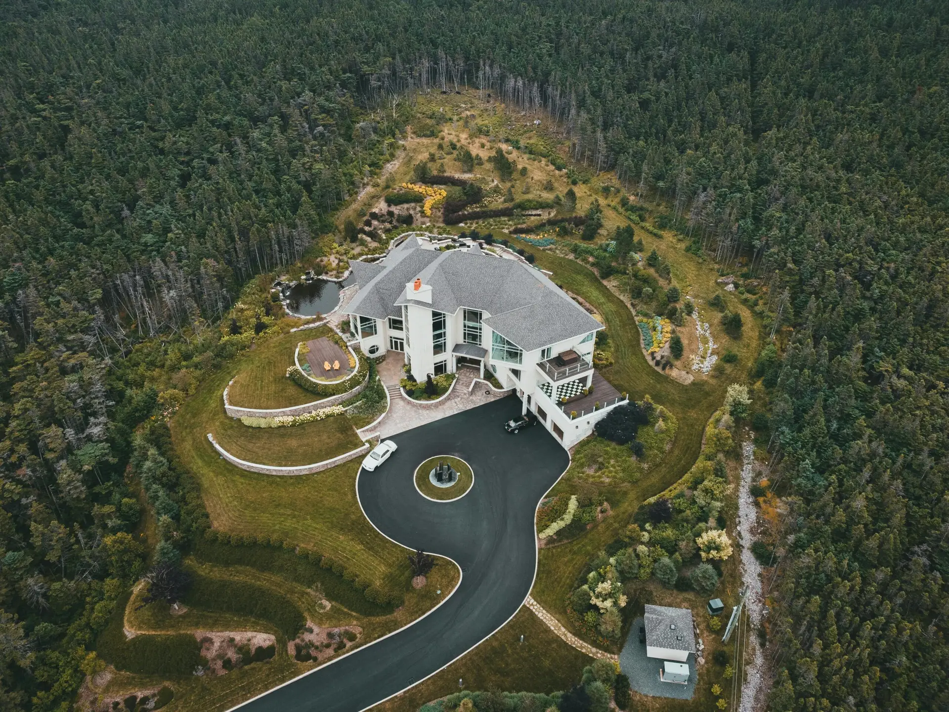 Drone shot of a luxurious house surrounded by dense forested landscape.
