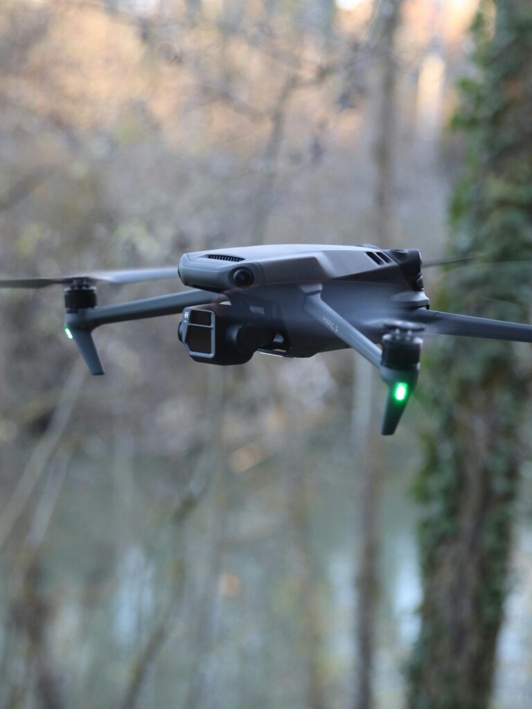 Aerial drone hovering in a wooded area, showcasing technology against nature.